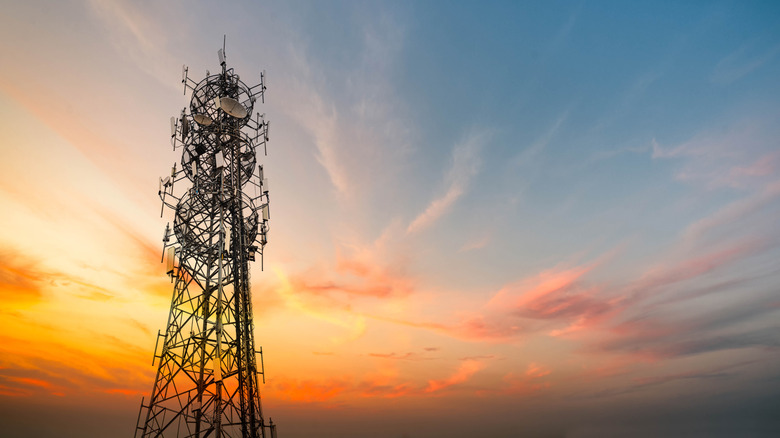 A cell phone tower in a remote area with a sunset sky in the background