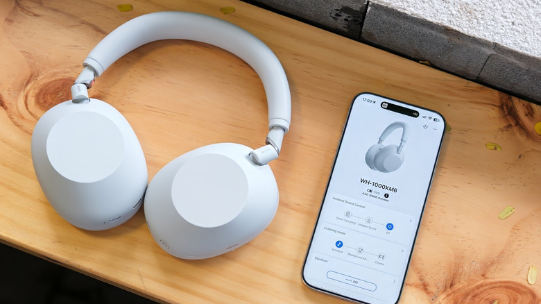Sony WH-1000XM6 headphones next to a smartphone with companion app open