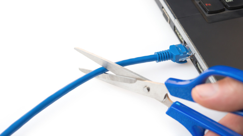 cutting ethernet cable connected to laptop