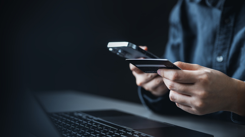 man holding a phone in one hand and credit card in another