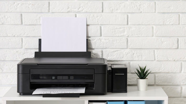 A printer loaded with paper, placed on a shelf.