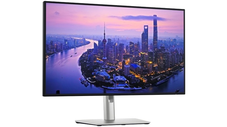 A Dell Ultrasharp U2725QE monitor displaying a purple-pink city skyline against a white background