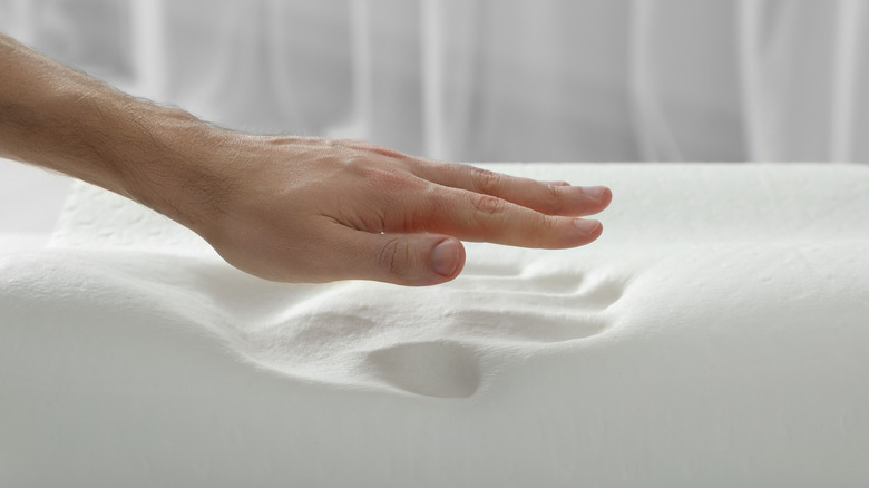 a hand pressing off a memory foam mattress