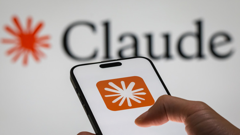 Person holding smartphone running Claude AI with logo in background
