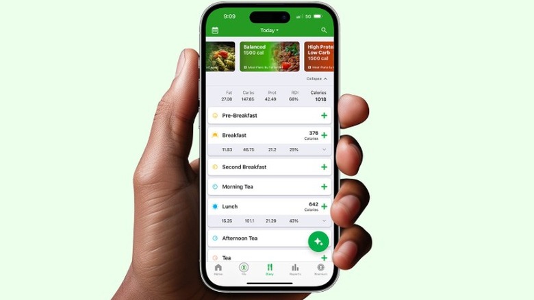 A person holding an iPhone showing the FatSecret app homescreen.
