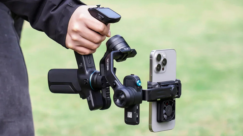 A person holding the FeiyuTech Scorp Mini 3 Pro gimbal, with a phone attached to it