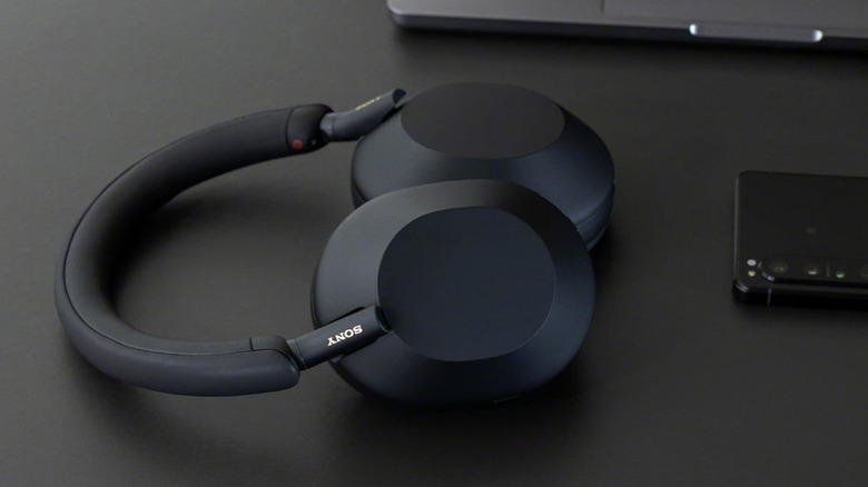 Sony headphones resting on desk next to smartphone and laptop