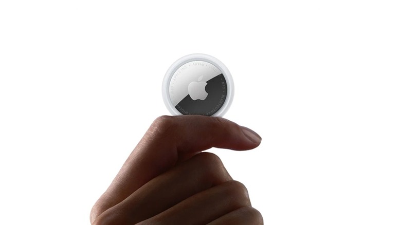 A person holding an Apple Air Tag (2nd Gen).