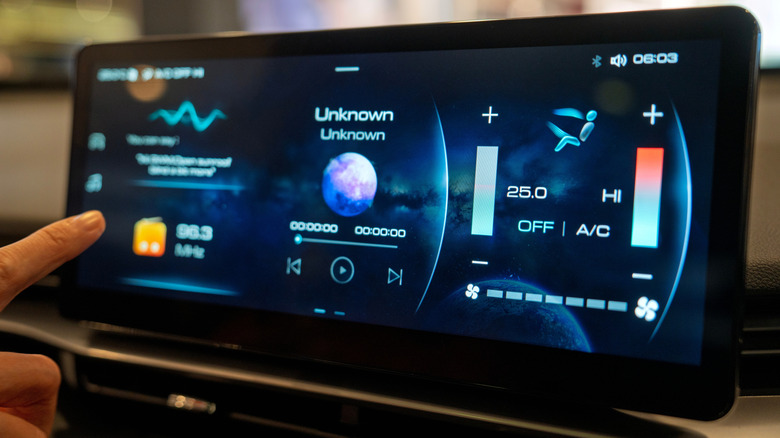 A close-up of the Haval H6 HEV's advanced infotainment screen showing climate control, music interface, and FM radio settings with a futuristic digital layout.