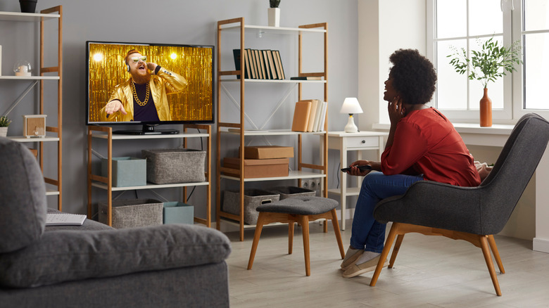 Woman in a red blouse watches an OLED TV in her living room.