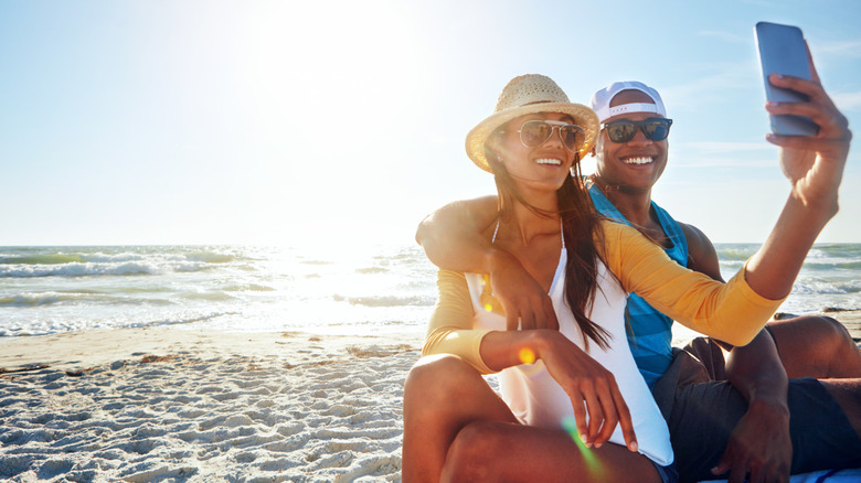 A happy couple taking a selfie on the beach
