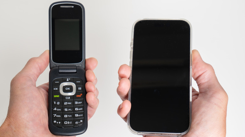 Two hands with one holding a smartphone and one holding a flip phone
