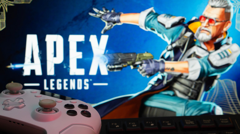A controller placed in front of a blurry Alex Legends logo on a screen