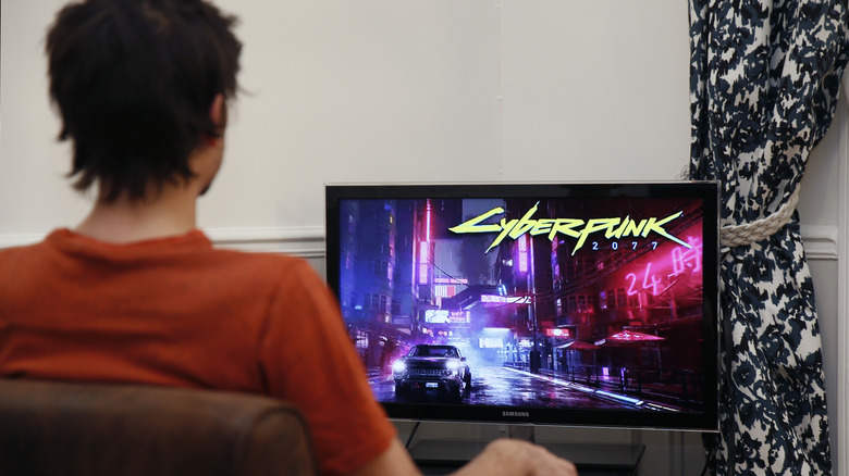 A person sitting in front of a monitor that's running Cyberpunk 2077