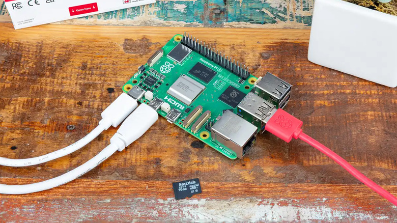 A Raspberry Pi 5 on a wood table with various cables connected.