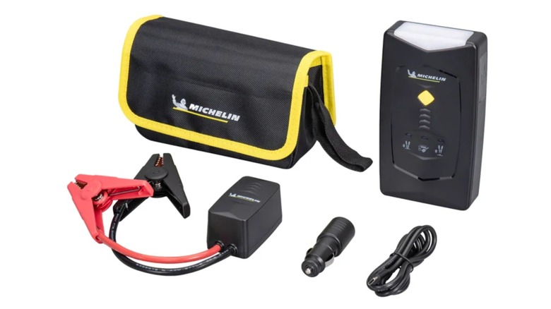 A promotional photo for the Michelin Portable Jump Starter, featuring the device, it's jumper cable pack, charging cable, and travel bag