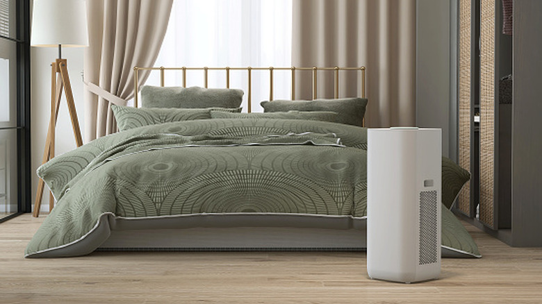 An air purifier at the foot of a bed.