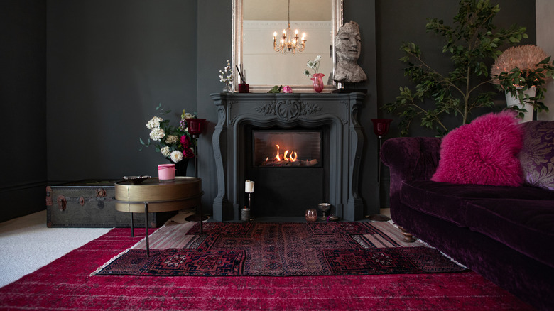 Contemporary living area with dark carpet and rugs on the floor and a velour sofa