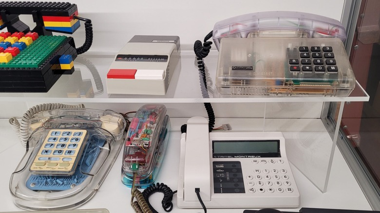 A display of various old-school telephones, including three with transparent cases