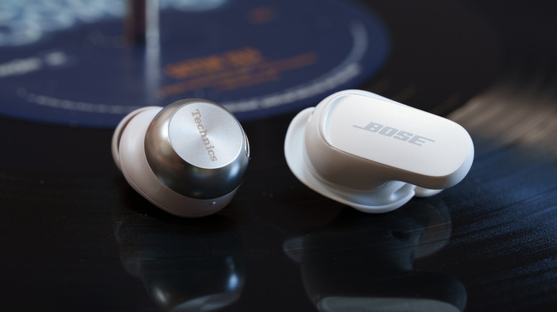 One Bose and One Technics earbud sitting on a record on a turntable