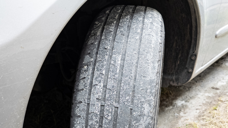 Close up of heavily worn car tire with treads nearly gone.