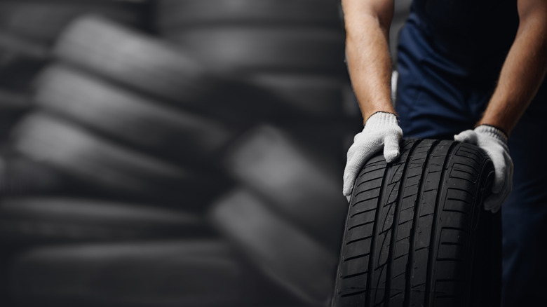 Mechanic rolling fresh tire with gloves on.
