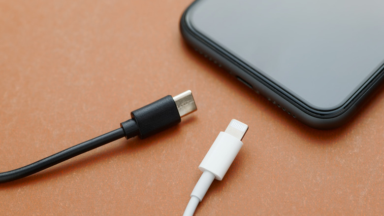 Two USB-C cables next to a phone with a USB-C charging port.