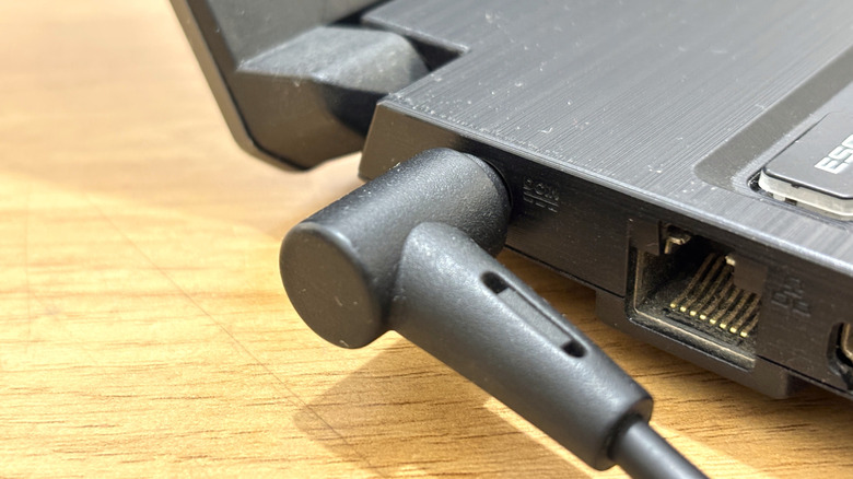 A laptop placed on a wooden surface with the charger plugged in