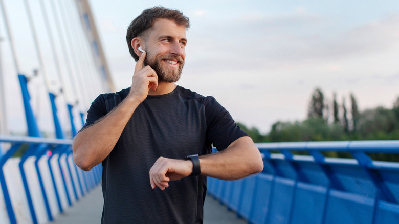 A man adjusting his earbuds after a run