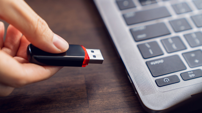 A person plugging a USB drive into a computer
