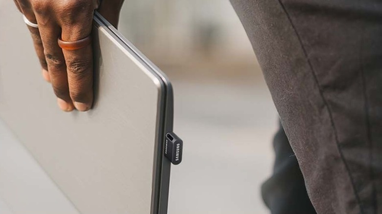 A person holding a laptop with a Samsung Fit Plus inserted