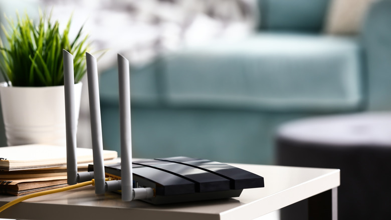 A router on top of a table next to plant and books in the living room