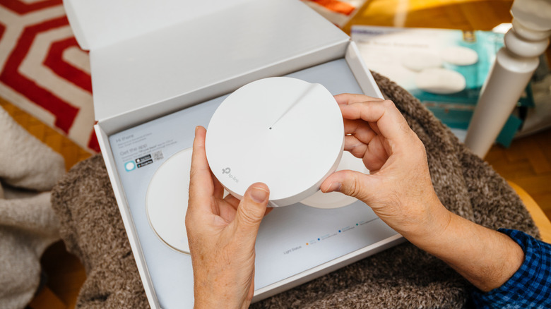 Close-up of a person handling mesh Wi-Fi router equipment