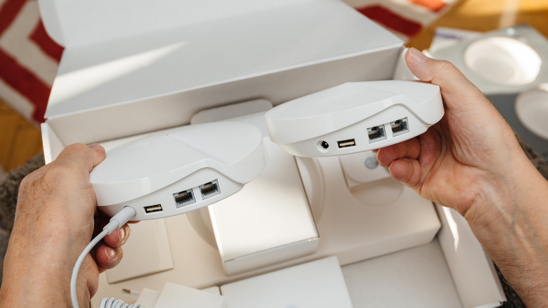 Close-up of a person handling mesh Wi-Fi nodes