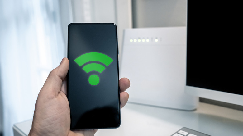 Close-up of a hand holding a smartphone showing a graphic representing strong Wi-Fi signal