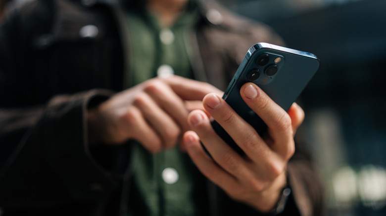 Close-up of a man's hands as he uses a blue iPhone