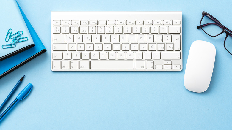 A white wireless keyboard and mouse on a light blue background.
