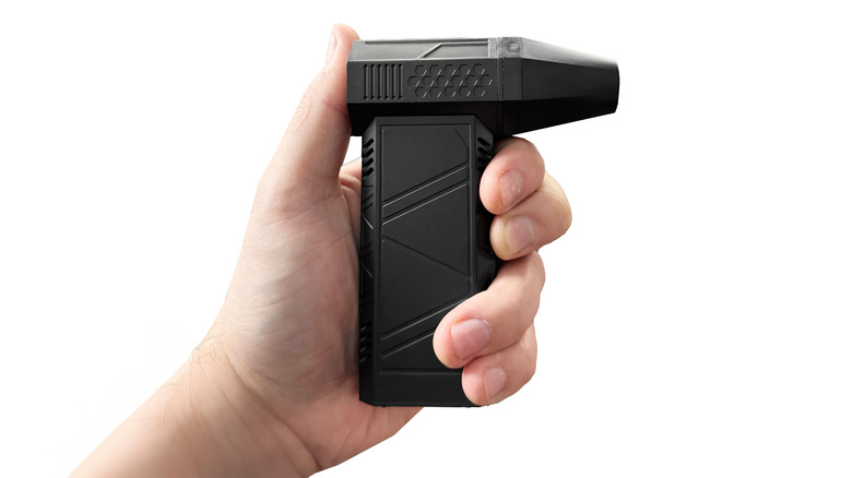 A hand holding an electronic compressed air duster.