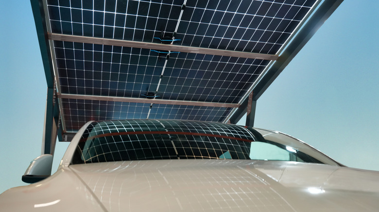 A car situated under a solar panel.