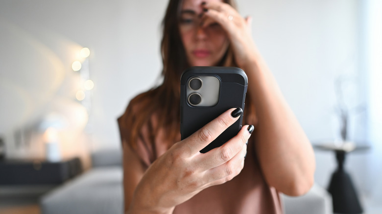 woman looking at smartphone in frustration