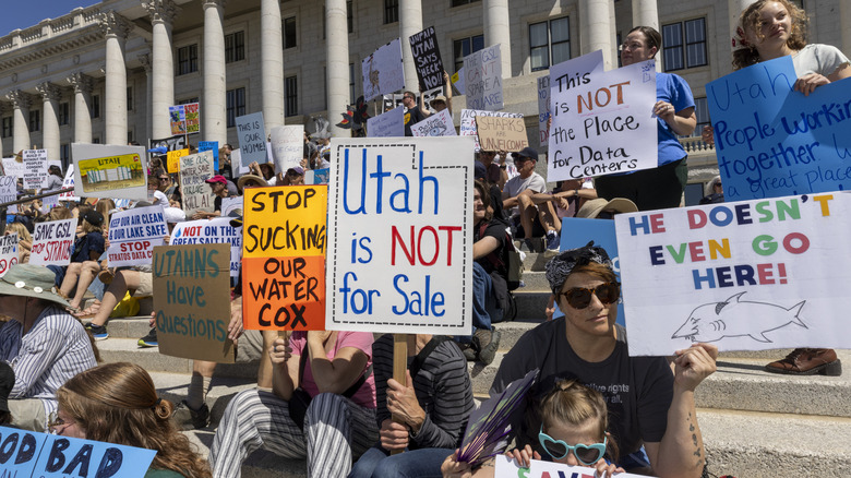 Protesters with signs in front of the Utah State Capitol opposing a new data center