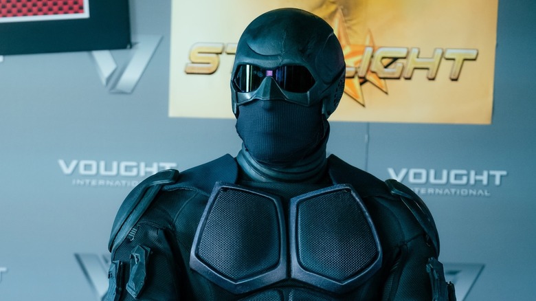 Black Noir (Nathan Mitchell) stood in front of a Vought display in The Boys