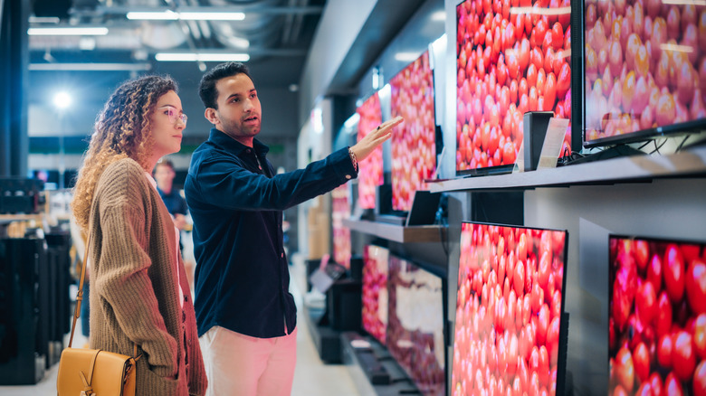 A man and a woman looking at TVs in a store