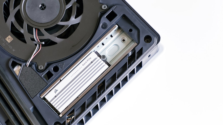 A PlayStation 5 with its side panel opened and the SSD slot featuring a drive exposed