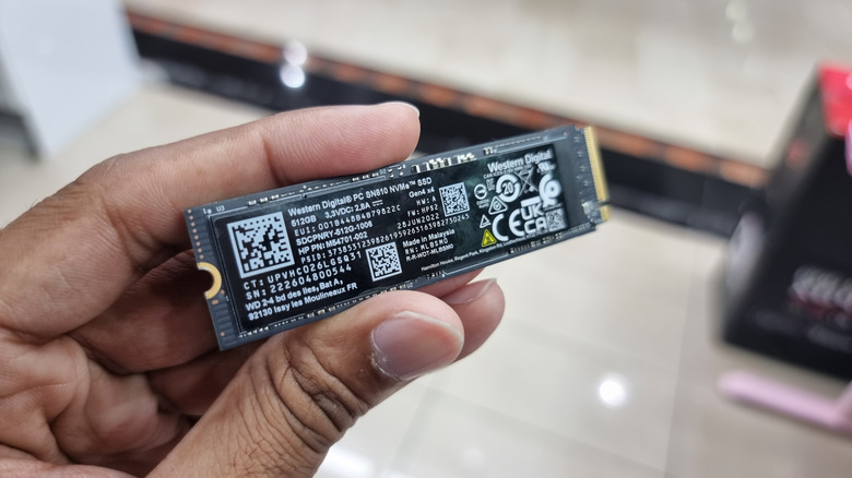 A hand holding a WD Black SSD NVMe drive