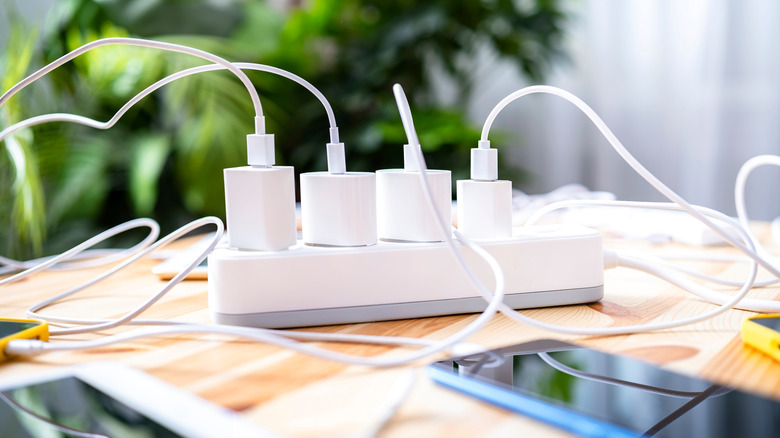 Multiple charging adapters plugged into a power strip with wires visible.
