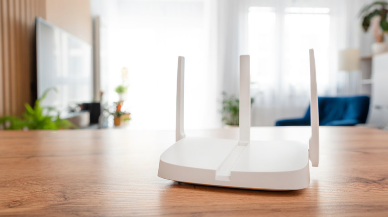 Modern Wi-Fi router on a table with a living room setting in the background.