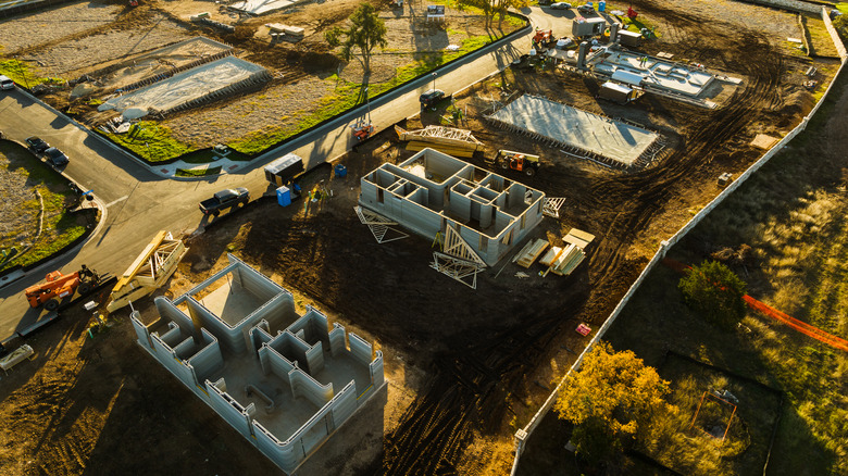 Aerial view of a construction site with multiple 3D-printed building structures in progress.