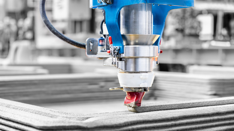 Large-scale 3D printer extruding layers of concrete material.