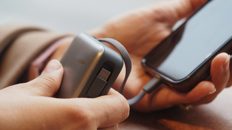 A person using a generic power bank to charge a smartphone.
